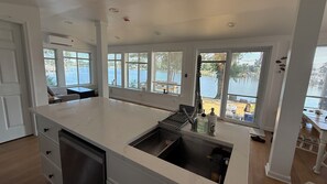 Una cuina moderna amb una illa gran, electrodomèstics integrats i grans finestres amb vista a un llac.
