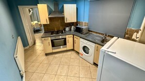 Cocina compacta con estufa, horno, microondas, tostadora, fregadero y lavadora.