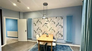Un comedor con una mesa y sillas de madera, un papel tapiz estampado y un radiador.