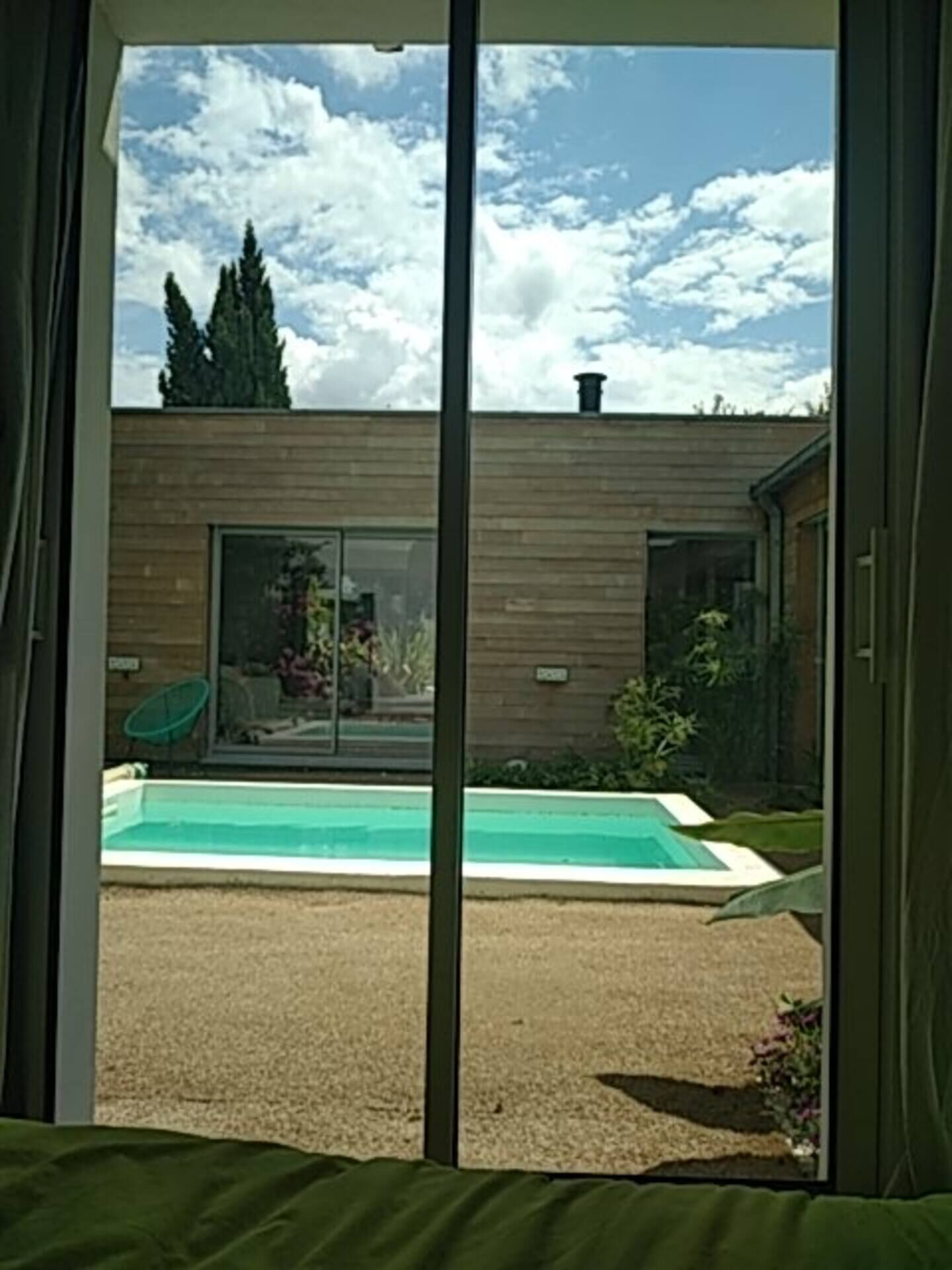 A modern building with a pool, a sliding glass door, and a view of the sky.