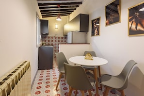 A compact kitchen with a refrigerator, a sink, and a window. There is a dining area with a table and chairs. - Lovely Campuccio by MMega (Firenze)