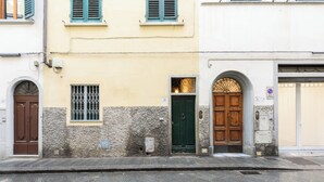 Vista de la calle con un edificio que tiene una puerta verde, una puerta marrón y una ventana con barrotes.