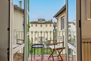 Un balcón con vista a un edificio, una mesa pequeña y una silla.