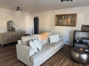 A living room with a sofa, a dresser, a painting, and a small round table.