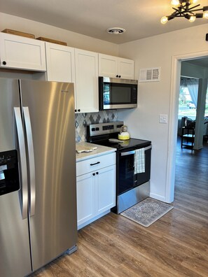 A kitchen with stainless steel appliances, white cabinets, a microwave, and a stove.