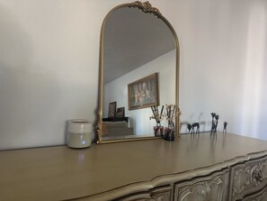 A mirror with an ornate frame on a dresser, a candle, and decorative items. - Golden Hour Getaway, tucked less than a mile from Frontier Park and downtown! (Cheyenne)