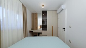 Ett hotellrum med en säng, ett skrivbord, en garderob och en luftkonditioneringsanläggning.