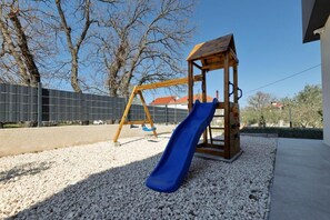 Ein Spielplatz mit einer Holzschaukel und einer blauen Rutsche.