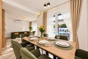 Un coin repas avec une table en bois dressée pour quatre personnes, entourée de chaises à l’assise verte.