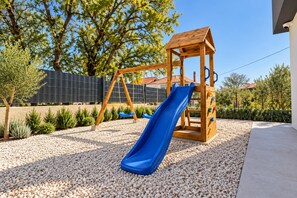 Un parque infantil con un sube y baja de madera y un tobogán azul.
