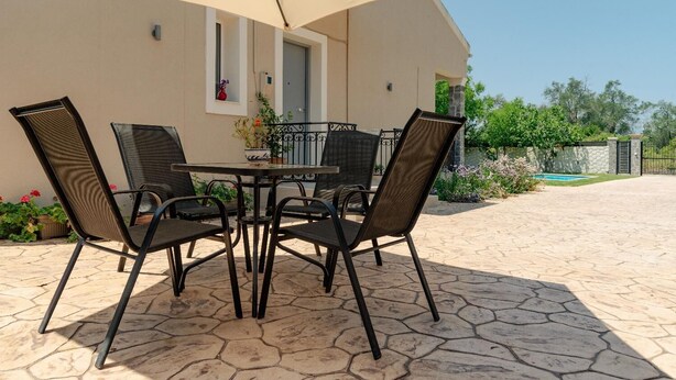 Eine Terrasse mit Tisch und Stühlen, einem Blumentopf und Blick auf einen Swimmingpool.