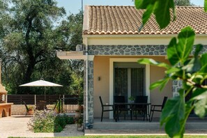 Ein Gebäude mit Ziegeldach, Steinwänden und einer Terrasse mit Gartenmöbeln.