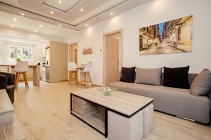 A modern living room with a sofa, a coffee table, and a dining area with chairs. - Villa Boltado - Two Bedroom Villa, Sleeps 4 (Lefkimmi)