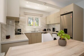 A modern kitchen with a built-in washing machine, a coffee maker, and a refrigerator. - Villa Boltado - Two Bedroom Villa, Sleeps 4 (Lefkimmi)