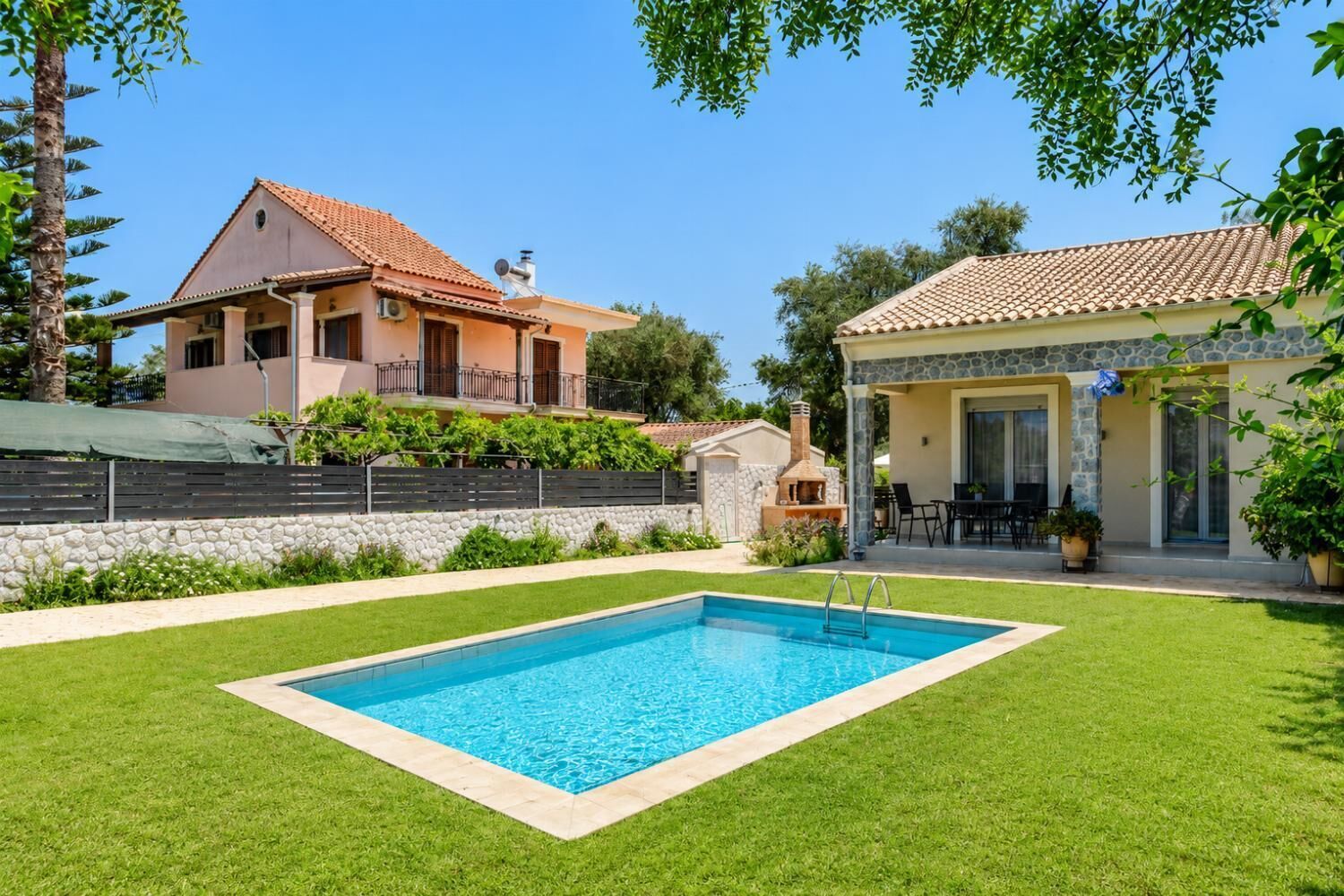A residential property with a swimming pool, stone walls, and a patio area.