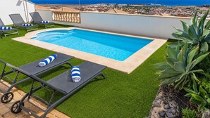 Piscina no terraço com grama sintética, espreguiçadeiras e vista para o oceano.