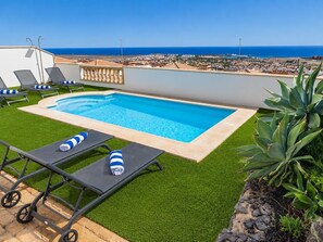 Ein Pool auf dem Dach mit Kunstrasen, Liegestühlen und Blick aufs Meer.