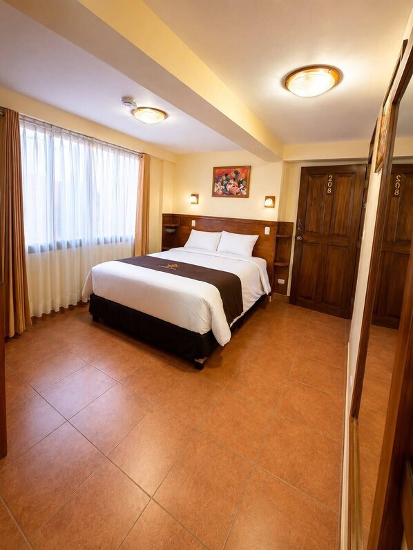 A hotel room with a large bed, a painting on the wall, and a door with the number 208.