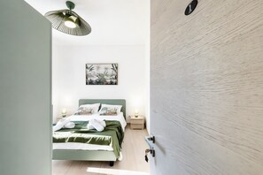 Un dormitorio con cama, lámparas de noche, una obra de arte en la pared y una puerta con placa numérica.
