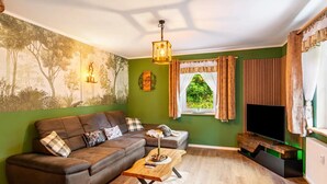 A living room with a sectional sofa, a coffee table, a television, and a window with curtains.