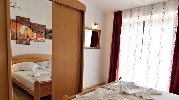 Een hotelkamer met een houten bed, een spiegel en een schilderij van vogels aan de muur.