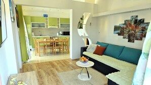 Een moderne woonkamer met een bank, een salontafel en een eethoek met een tafel en stoelen.