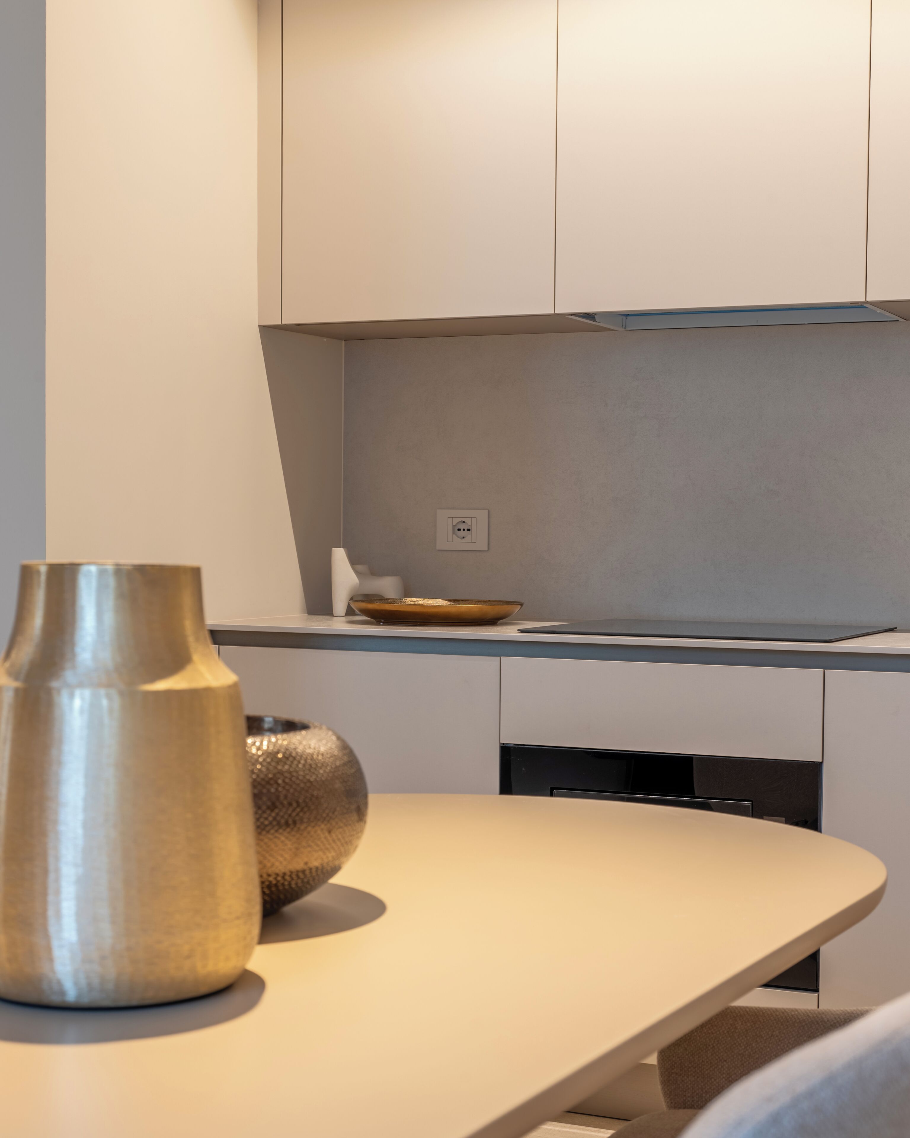 A modern kitchen with a white countertop, a vase, and a bowl.