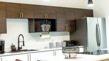 A modern kitchen with dark wood cabinets, stainless steel appliances, a red chair, and a black and white patterned tray.