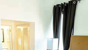 Ein Hotelzimmer mit Bett, Nachttisch, Lampe und Kleiderschrank.