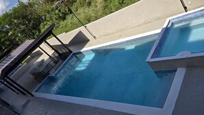 Ein Schwimmbecken mit glatter, blauer Wasseroberfläche, umgeben von einer Betonplattform und einem Metallgeländer.