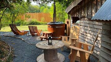 Un espace extérieur aménagé en bois, avec un coin salon, un jacuzzi, une table et des chaises.