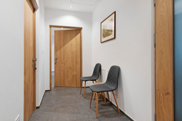 A hallway with two chairs, a wooden door, and a framed picture on the wall. - Apartment 'Trostburg' with Mountain View and Wi-Fi (Barbian)