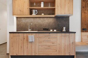 Une cuisine avec des meubles de rangement en bois, un évier en acier inoxydable et un plan de travail.