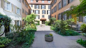 A courtyard with a central garden, surrounded by buildings with multiple windows and balconies.
