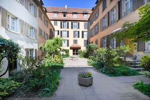 Un patio central con un jardín, rodeado de edificios con varias ventanas y balcones.