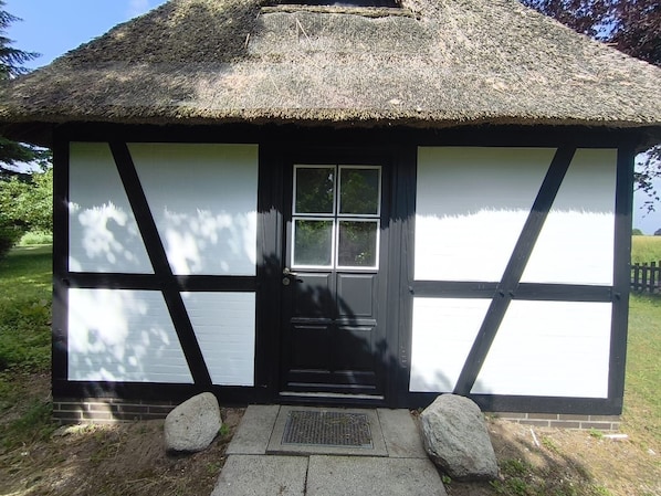 A traditional thatched-roof cottage with a black door, white panels, and a small window. - Cozy vacation home in a quiet location, 3 km from the Schlei, with beaches 20 minutes away (Boren)