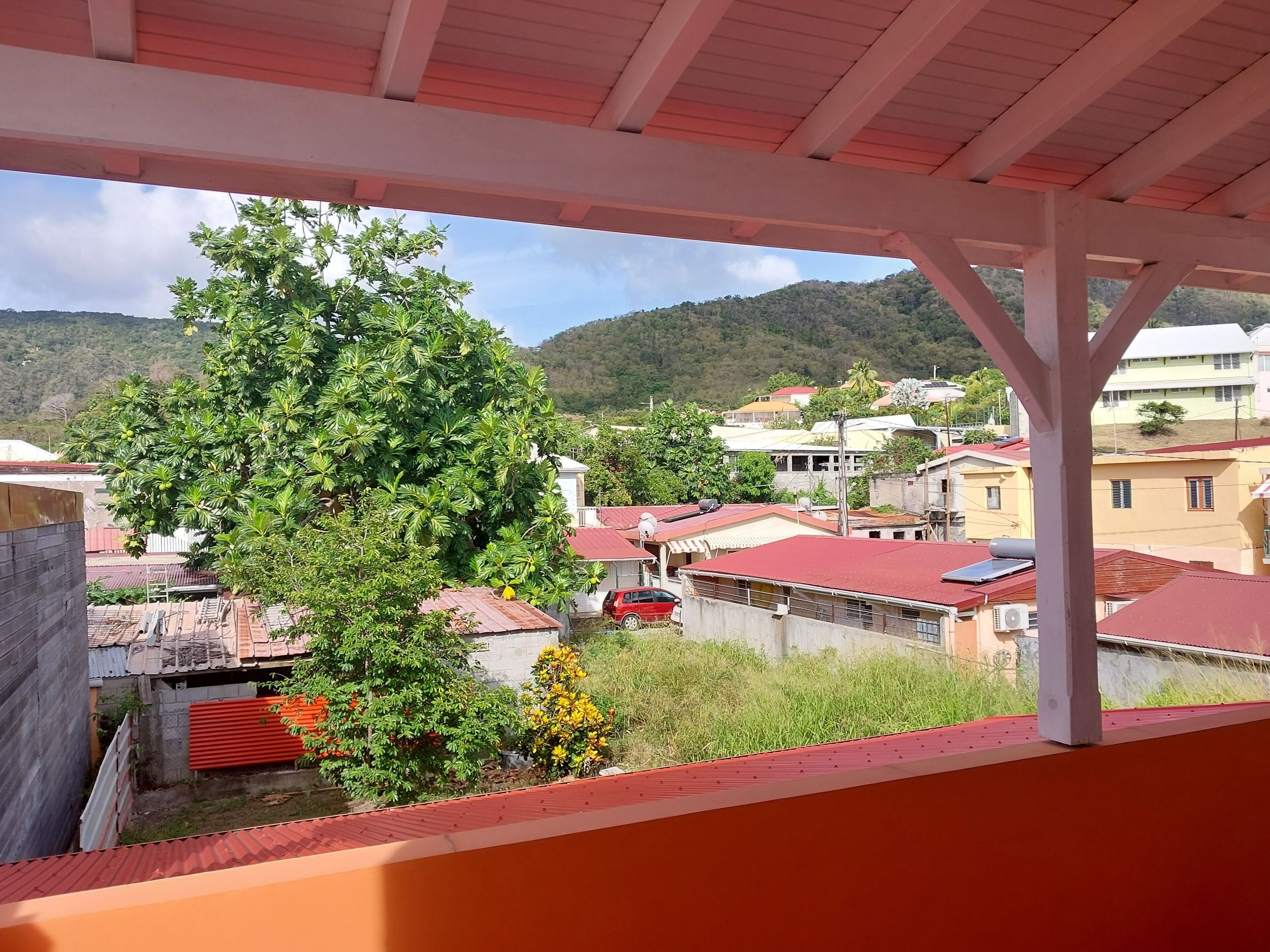 A residential area with houses, a tree, and a red car.