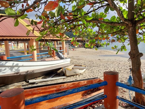 Ein Küstenabschnitt mit Bootsanlegestelle, überdachtem Sitzbereich und Sandstrand.