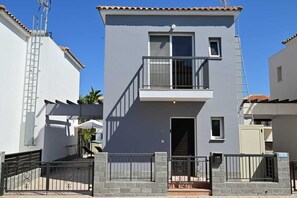 A two-story residential building with a balcony, a gated entrance, and a solar panel on the roof.