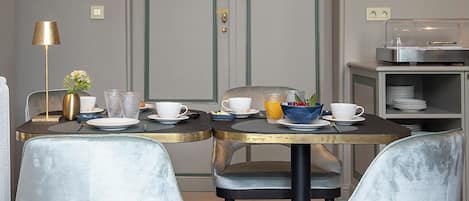 Een eetruimte met een tafel gedekt voor vier personen, twee stoelen, een lamp en een deur op de achtergrond.