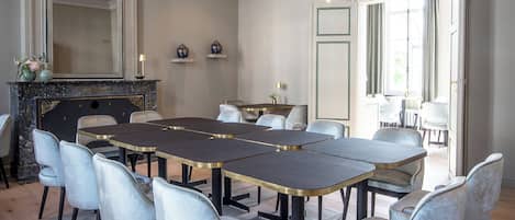A conference room with a large rectangular table surrounded by chairs, a fireplace, and a large mirror on the wall.