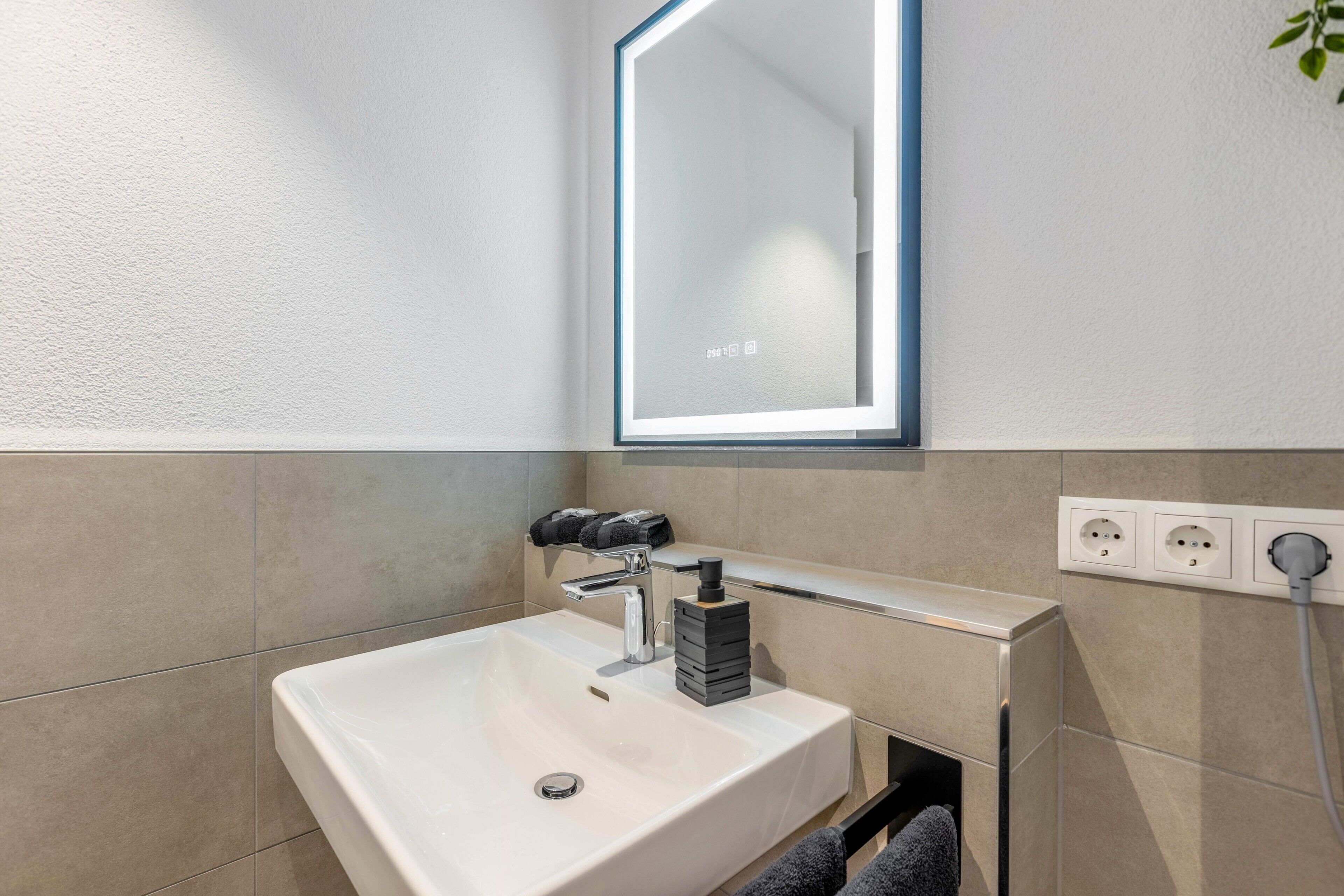 A modern bathroom with a white sink, a mirror, and a towel rack.