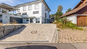 Ein modernes, zweistöckiges Gebäude mit einer gepflasterten Auffahrt, die zu einer Garage führt.