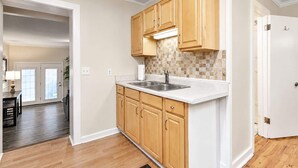 A kitchen with wooden cabinets, a white countertop, and a tiled backsplash.