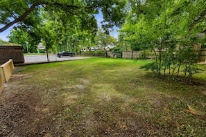A backyard with a wooden fence, a small tree, and a parked car. - The Fig, Pet-Friendly Home, Fenced Yard, Elon U (Burlington)