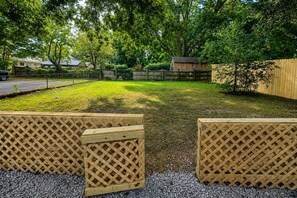 Un cortile con una recinzione in legno, un piccolo capanno e un vialetto sterrato.
