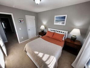 Una camera da letto con un letto, due comodini, una porta e un quadro appeso al muro.