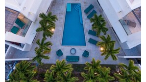A rooftop pool with a rectangular shape, surrounded by lounge chairs and palm trees. - Luxury Pool Villa 50 Steps From Stunning Beach Beautiful Views WEST TOWER ONLY (Moss Town)