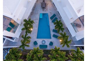 A rooftop pool with a rectangular shape, surrounded by lounge chairs and palm trees. - Luxury Pool Villa 50 Steps From Stunning Beach Beautiful Views WEST TOWER ONLY (Moss Town)
