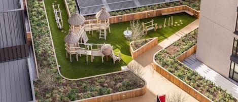 A rooftop garden with play structures, seating areas, and planters.